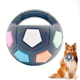 A durable black TPR squeaking dog soccer ball detailed with vibrant rainbow-striped panels and an integrated carrying handle loop.