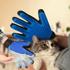 A blue silicone pet grooming glove being used to remove loose fur from a cat, with hair collected on the glove surface.