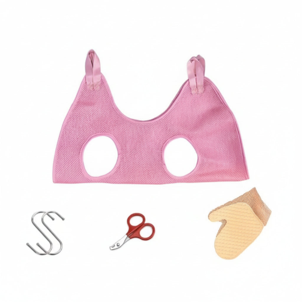 Pink pet grooming hammock displayed with included hooks, nail scissors, and grooming glove, designed for safe pet restraint during grooming tasks.
