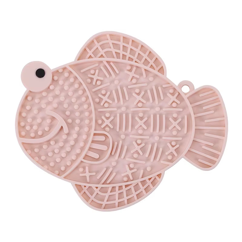 A pink fish-shaped textured silicone lick mat with a suction base for dogs and cats.