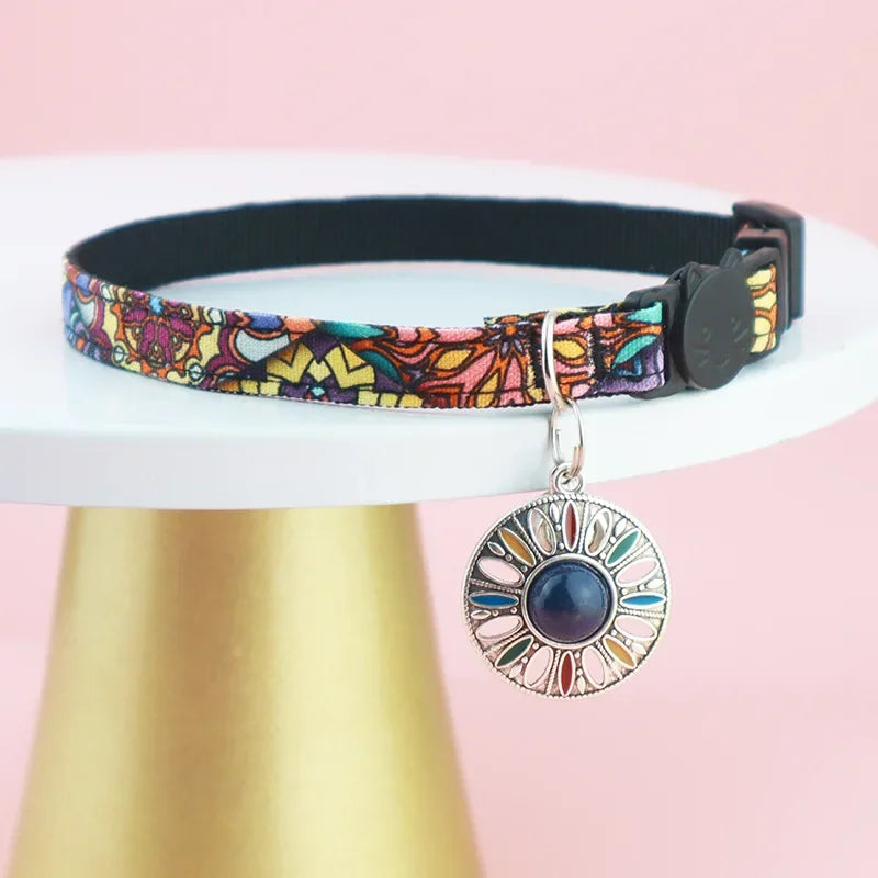 An adjustable navy blue breakaway AirTag cat collar featuring an intricate Bohemian print pattern and an integrated silicone tracker pocket.