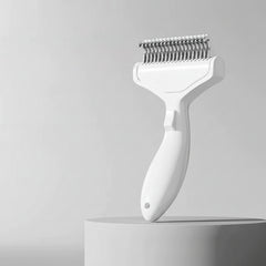 A white curved stainless steel grooming brush for long-haired pets featuring a professional ergonomic handle.
