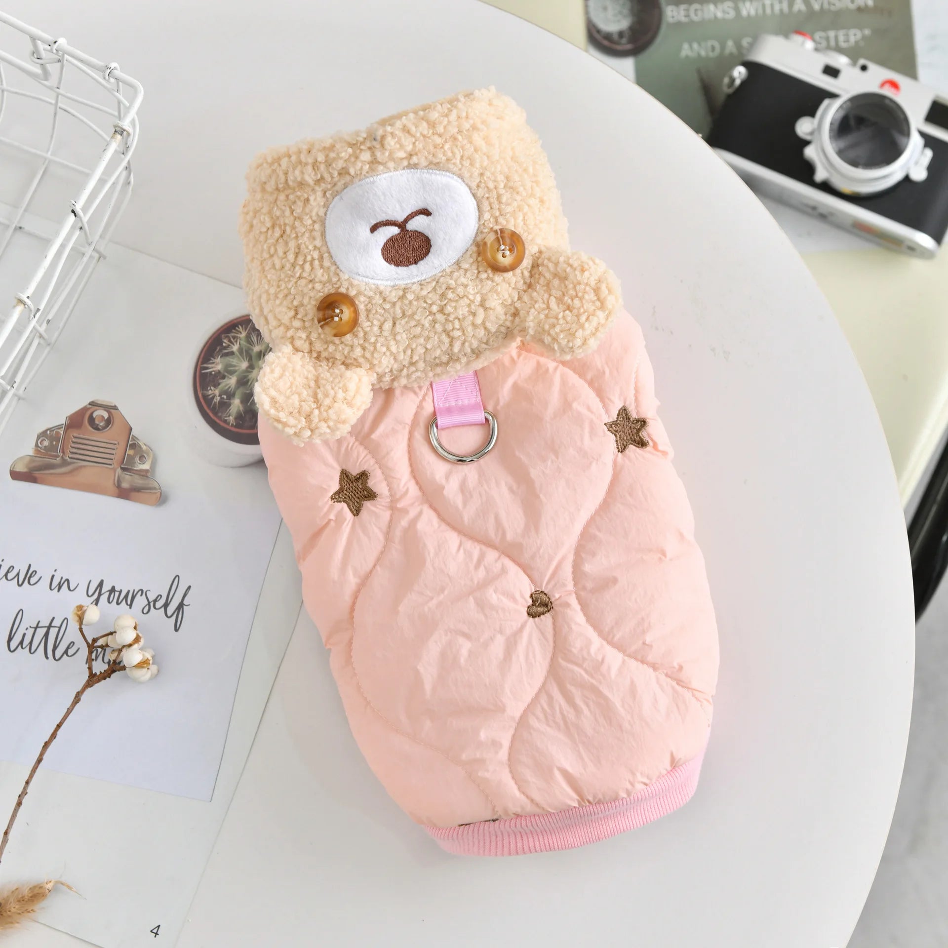 An insulated blossom sakura pink quilted winter pet jacket featuring an adorable plush bear accent, embroidered stars, and a secure metal leash D-ring.
