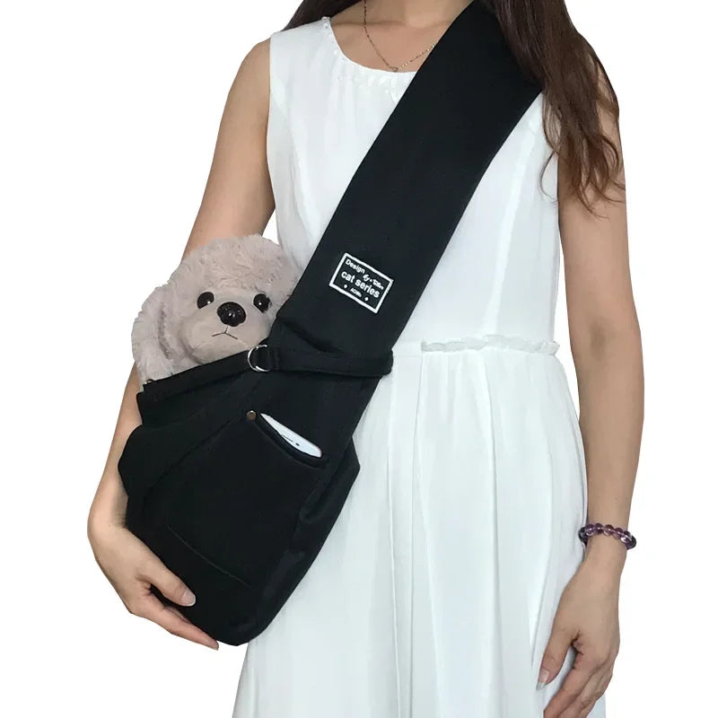A sleek stealth black crossbody pet sling carrier bag made from durable polyester fabric with a wide single shoulder strap and a front storage pocket.