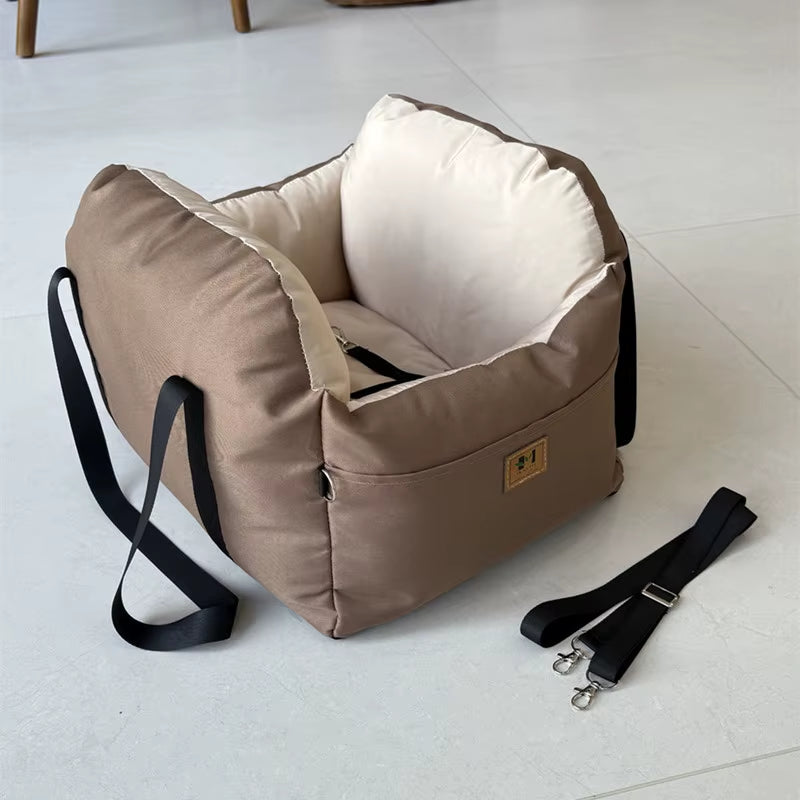 Brown soft dog car seat with beige interior cushion, safety belt, and side straps for secure pet travel.