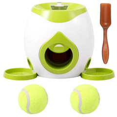 A sage green interactive mechanical dog tennis ball launcher and treat dispenser showing its top drop funnel, two catch trays, and included tennis balls.