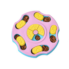 A rose quartz pink and yellow interactive dog puzzle toy slow feeder showing sliding paw-printed compartments filled with kibble.