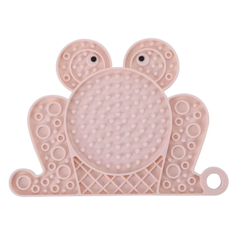A pink frog-shaped textured silicone licking mat for dogs and cats featuring a strong suction base.