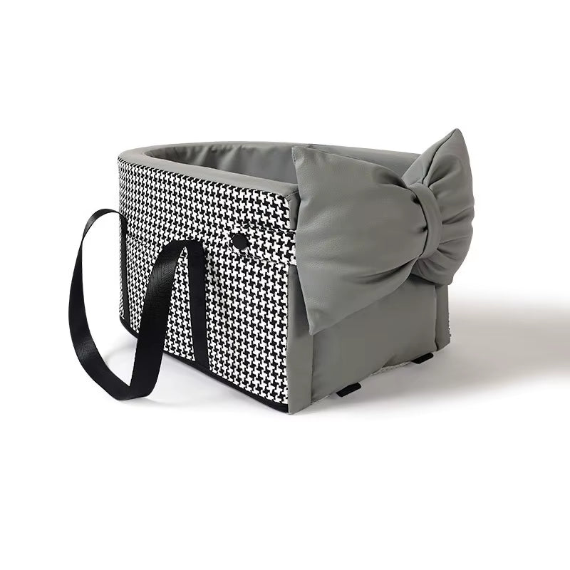 Black and white houndstooth pet car seat with grey bow, padded interior, and carrying straps for small dogs and cats.